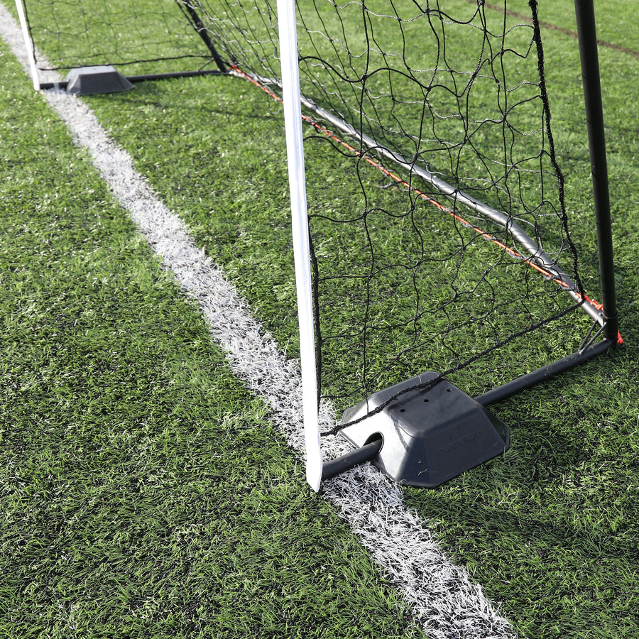 Base Weight set of 2 for KICKSTER, SPOT and agility poles: a black base weight sitting over the bottom bar at the corner of a goal on artificial grass.