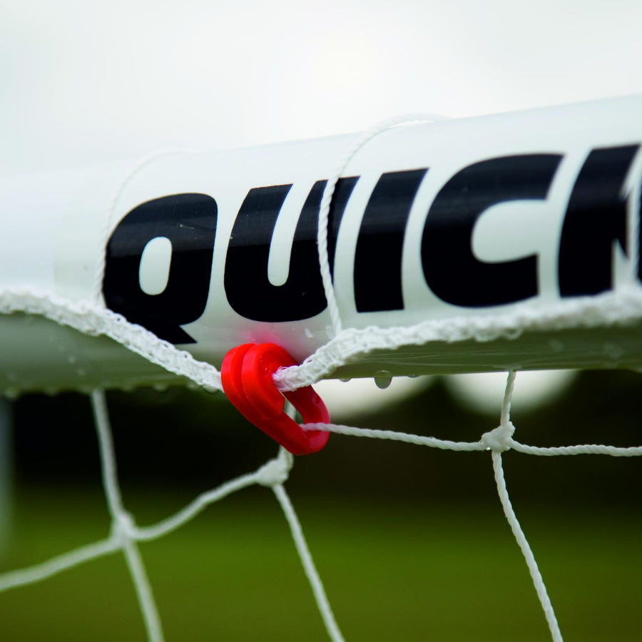 Close-up of a red net clip holding the white net to the Q-FOLD Mini 90 x 75 cm crossbar, under QUICKPLAY lettering.