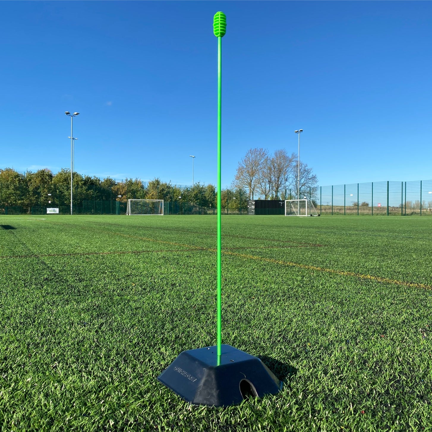 Base Weight set of 2 for KICKSTER, SPOT and agility poles: a single base weight holding one tall green pole on an artificial pitch.