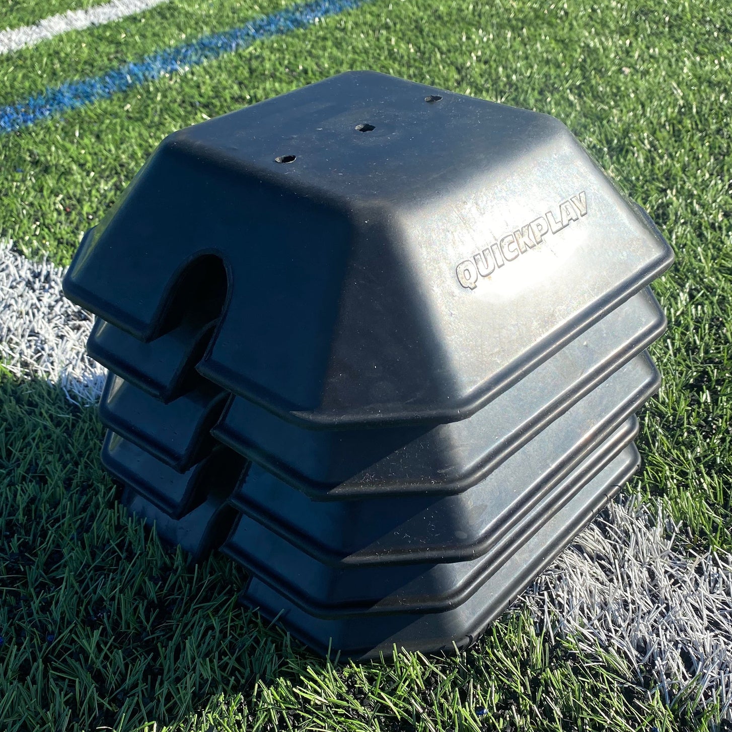 Base Weight set of 2 for KICKSTER, SPOT and agility poles: black QUICKPLAY base weights stacked on top of each other on artificial grass.
