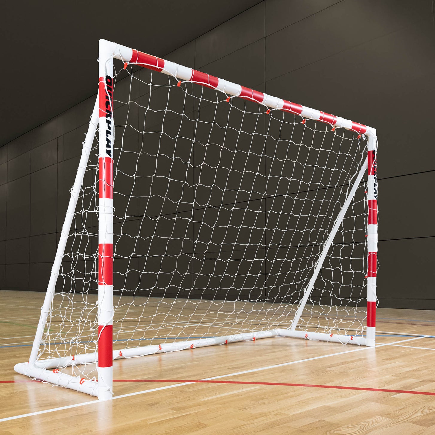 Q-FOLD Folding Handball Goal 300 x 200 cm with red and white striped posts and a white net, on a wooden sports hall floor.