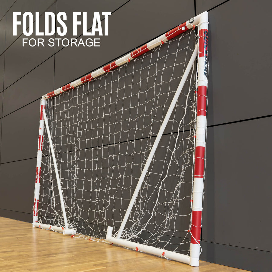 Q-FOLD Handball Goal 300 x 200 cm folded flat against a sports hall wall, with the text "Folds flat for storage".