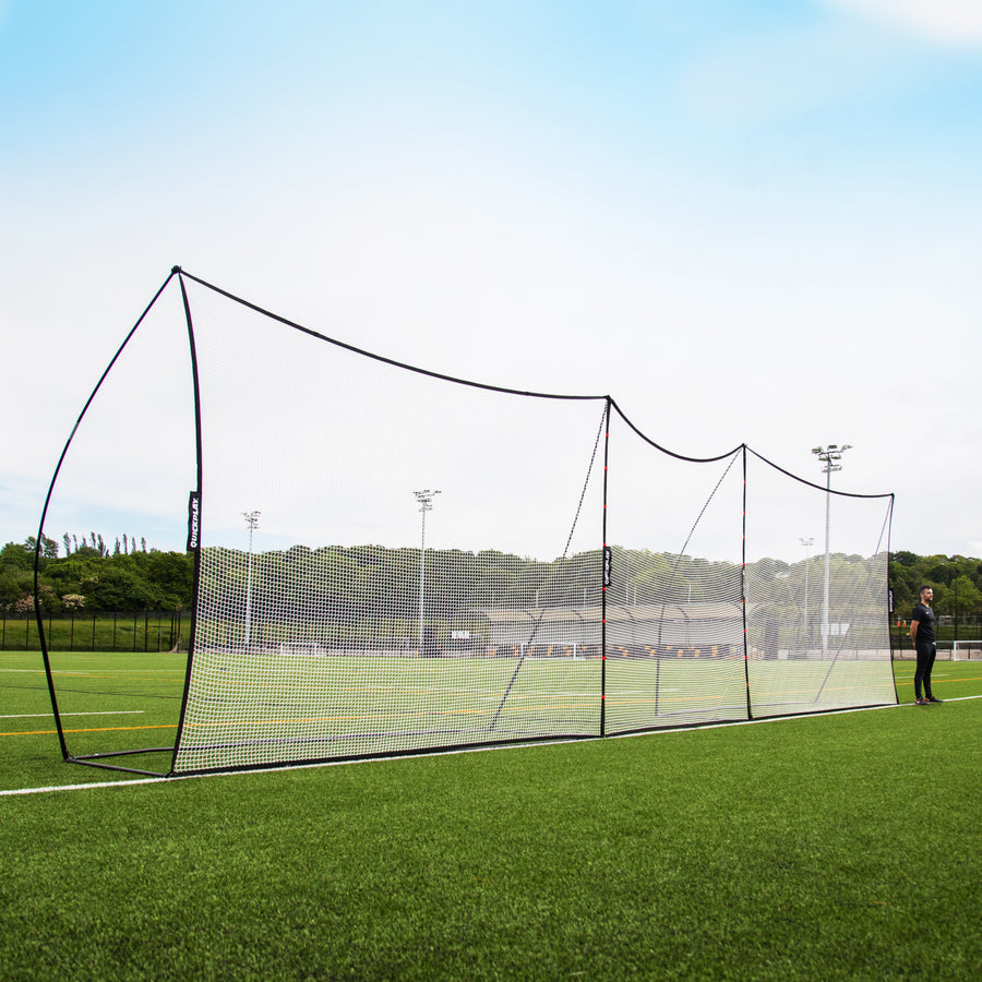 Extender Net 240 x 270 cm joining two MEGA NETs in the middle of a long ball-stop line on an artificial pitch, a man at one end.
