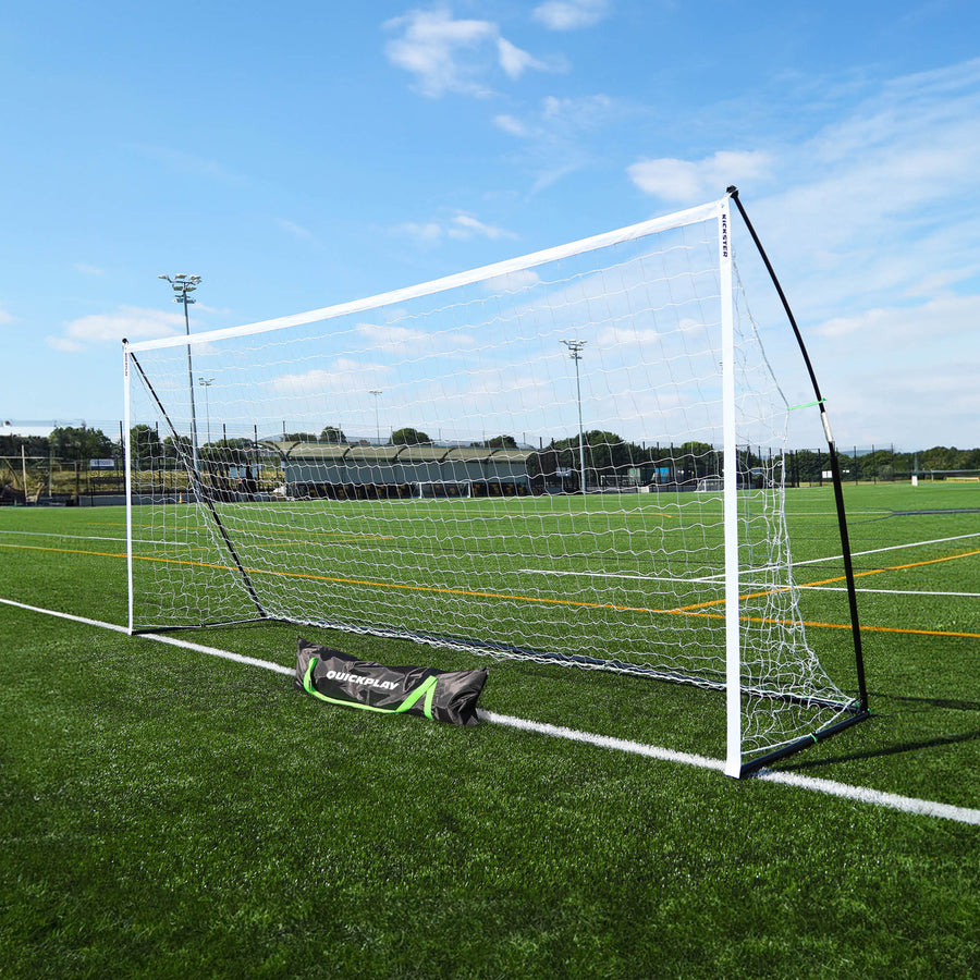KICKSTER Elite 500 x 200 cm goal on an artificial pitch, seen at an angle with its black QUICKPLAY carry bag in front.