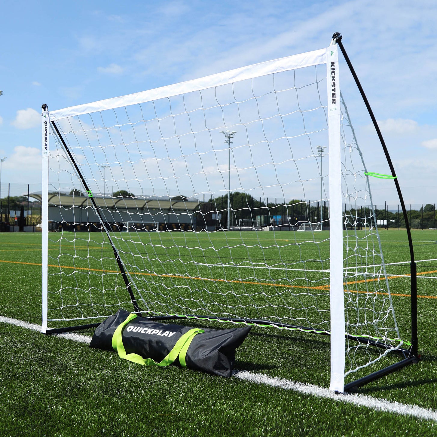 KICKSTER Elite 180 x 120 cm goal on an artificial pitch, with its black QUICKPLAY carry bag in front.