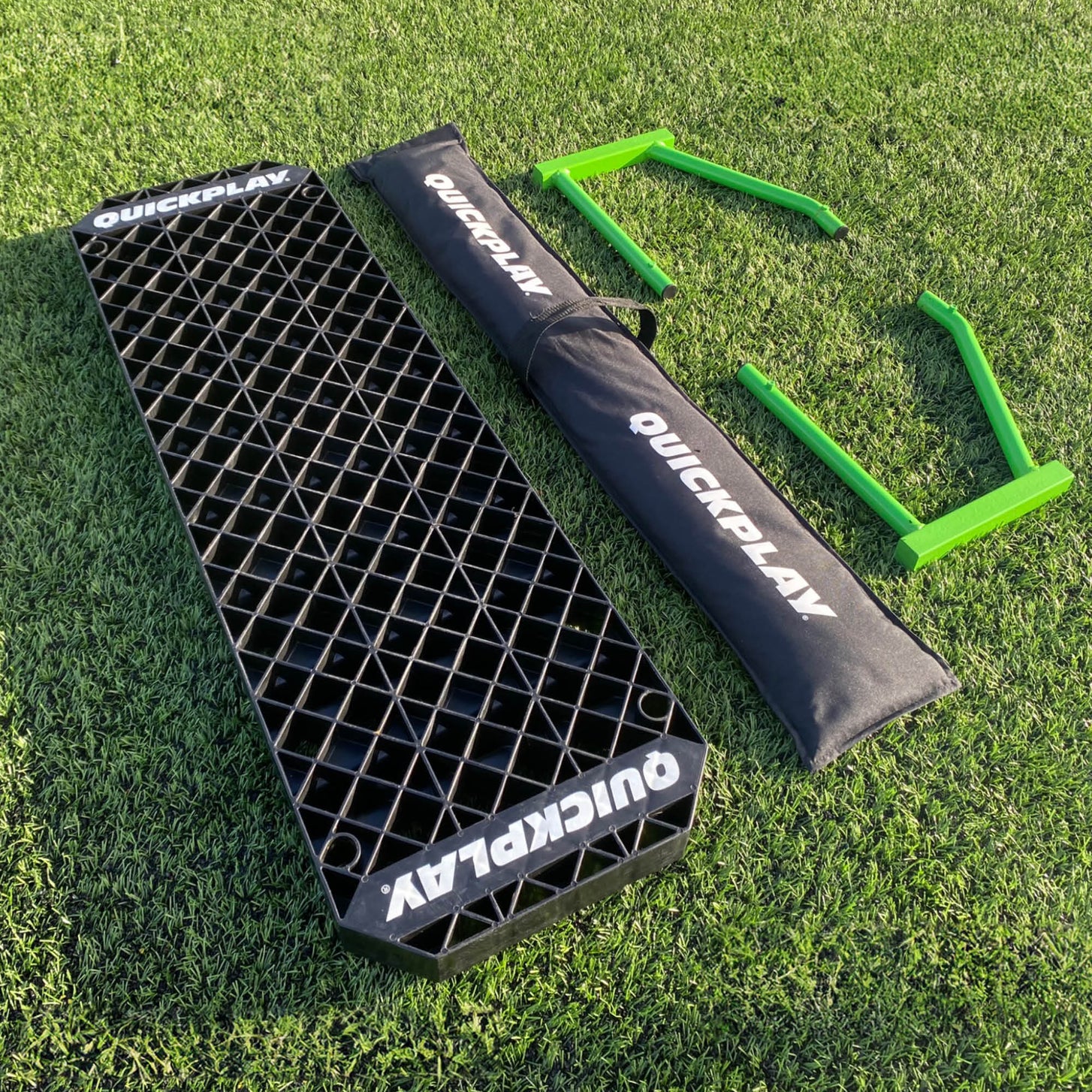 REPLAY Station XL parts laid out on grass: black board, black QUICKPLAY bag and two green frames.