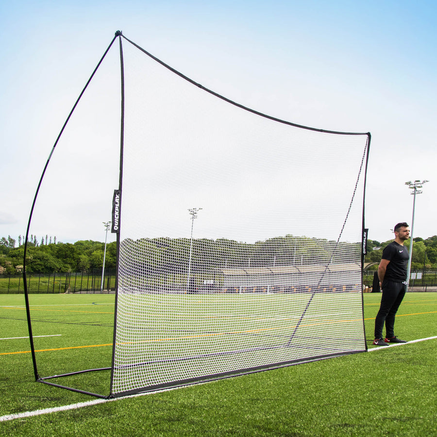 MEGA NET 370 x 270 cm ball-stop with a black frame and white net on an artificial pitch, a man standing beside it.