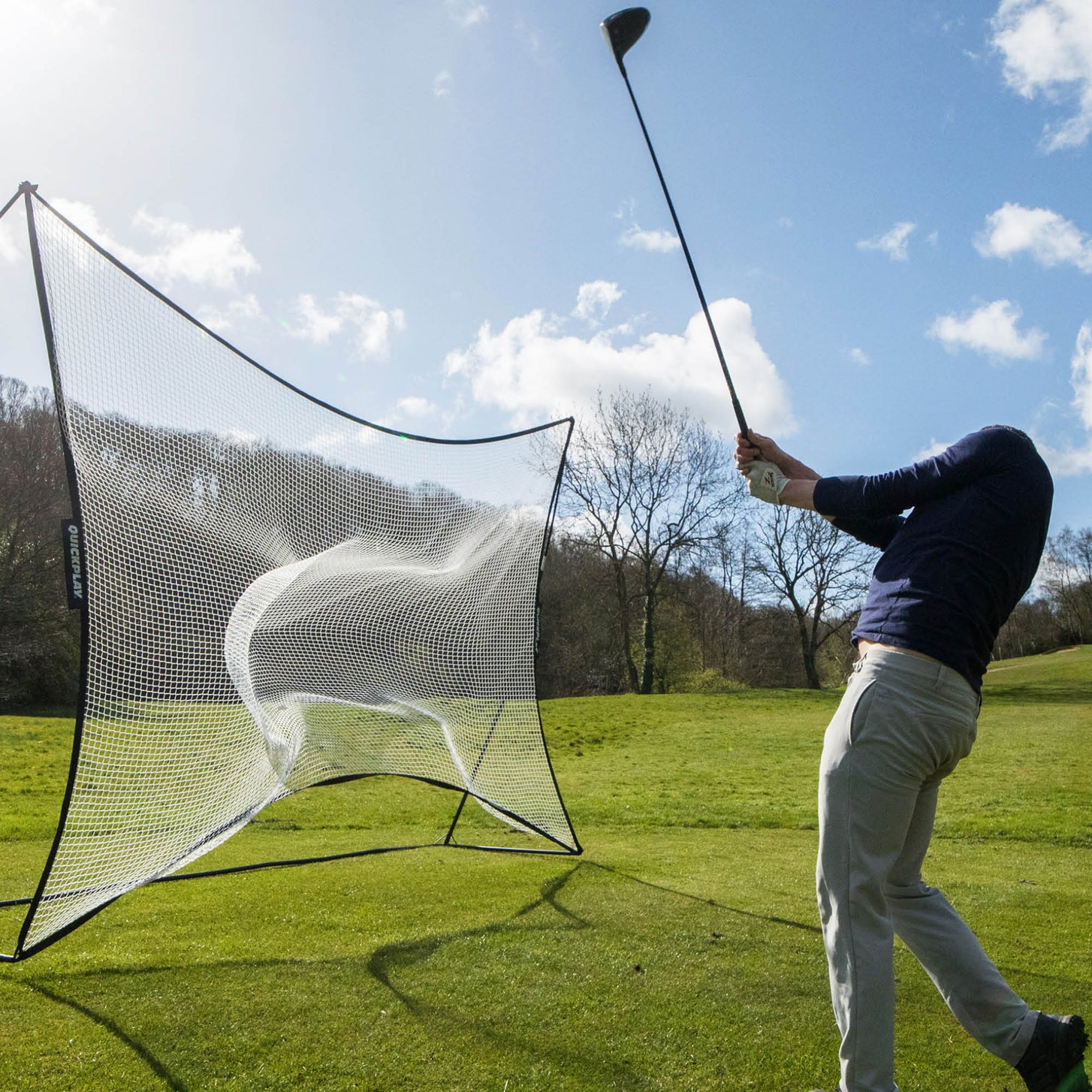 MEGA NET 370 x 270 cm ball-stop on a grass field, a golfer swinging a driver after hitting a ball into the net.