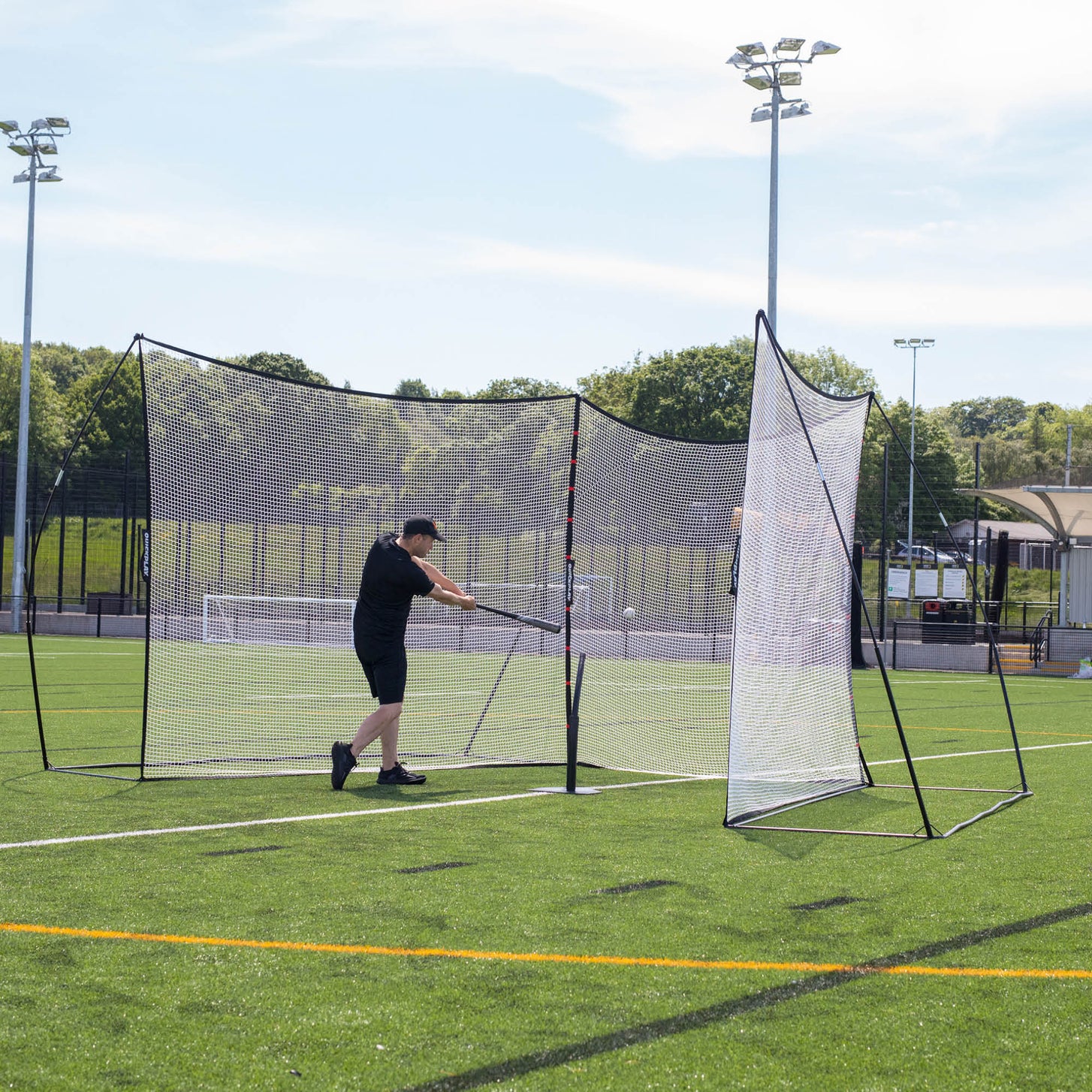 MEGA NET 370 x 270 cm ball-stops on an artificial pitch, a player hitting a baseball with a bat into the nets.