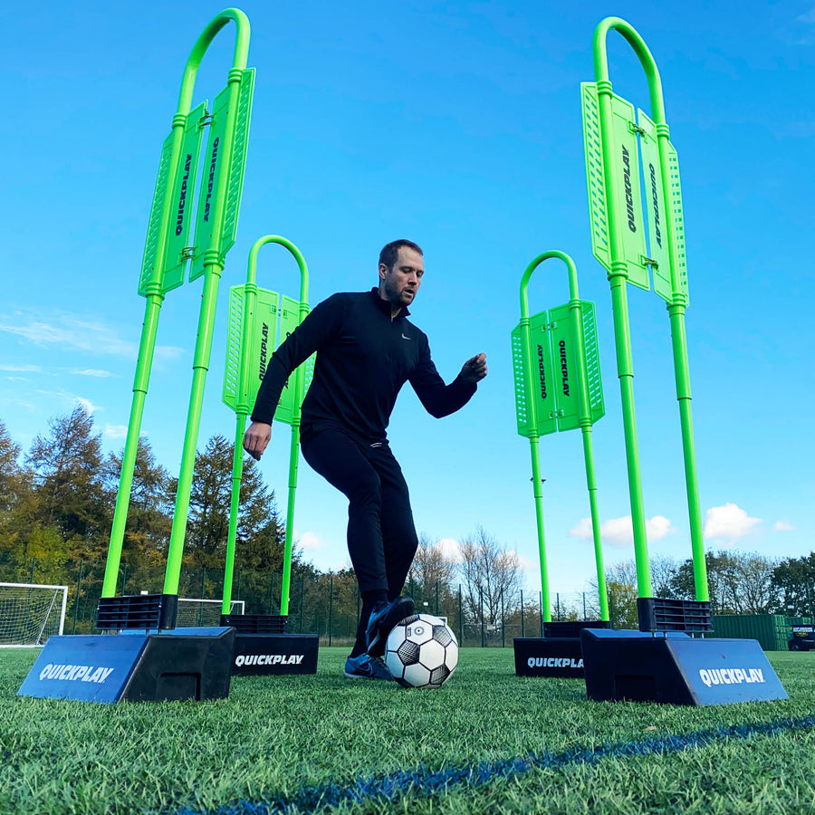 REPLAY Defender & Block System from a low angle: player dribbling a ball between four green mannequins in black bases.