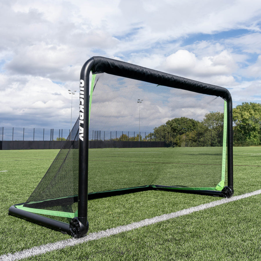 RHINO Football Goal 150 x 100 cm set up on an artificial pitch under a cloudy sky, with trees beyond the fence.