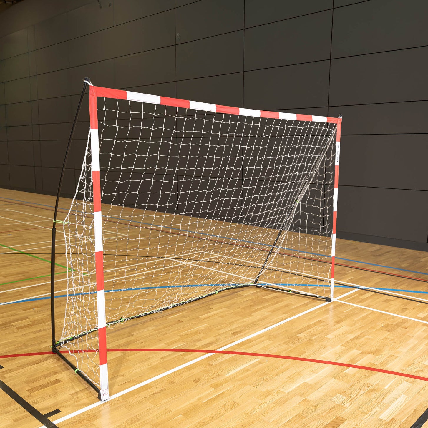 Portable Handball Goal Adult 300 x 200 cm with a red and white frame and white net, standing on a wooden sports hall floor.