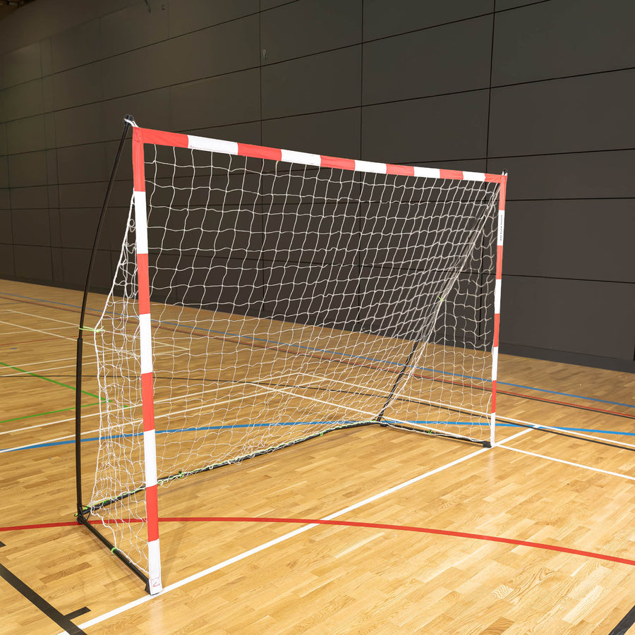 Portable Handball Goal Adult 300 x 200 cm with a red and white frame and white net, standing on a wooden sports hall floor.