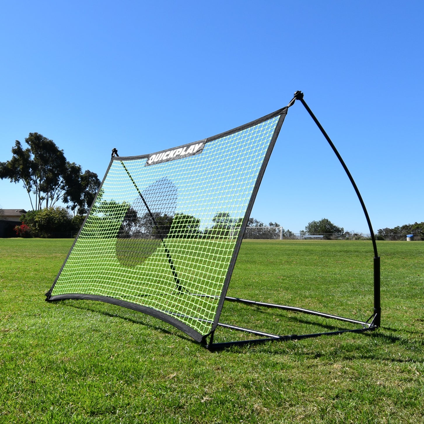 TEKKERS Net Football Rebounder 150 x 100 cm on grass in sunshine, seen from a front corner, with its green net.