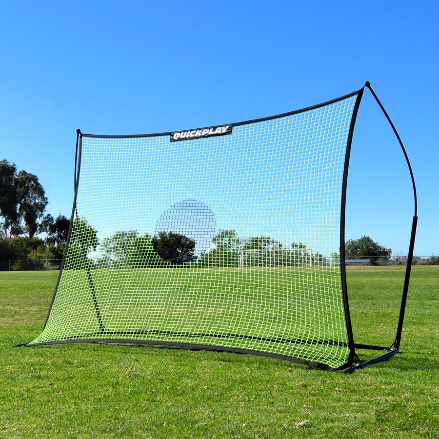 TEKKERS Net XL Football Rebounder 240 x 180 cm on grass under blue sky, seen from a front corner.