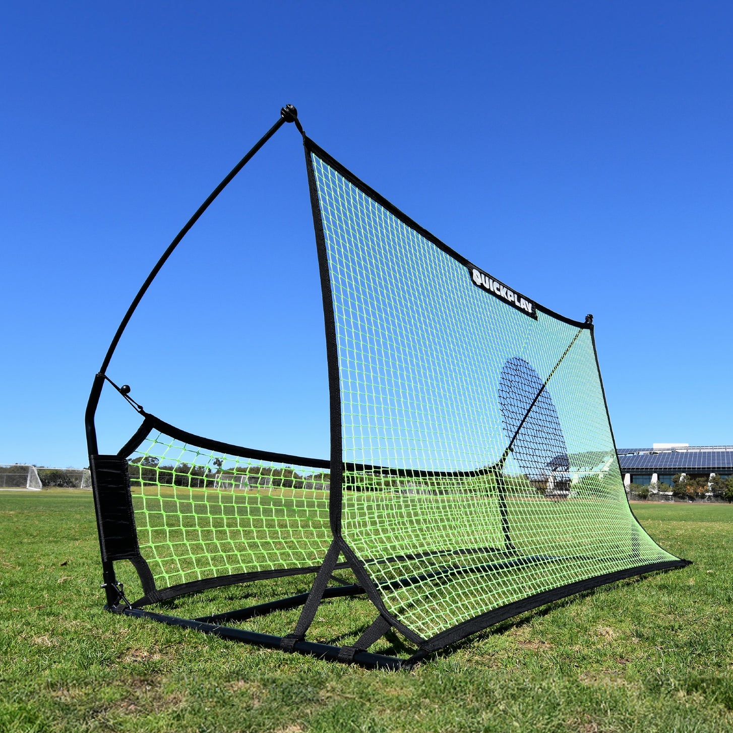 TEKKERS Trainer Dual Net Football Rebounder on grass, showing its large green net with a dark target circle and lower net.